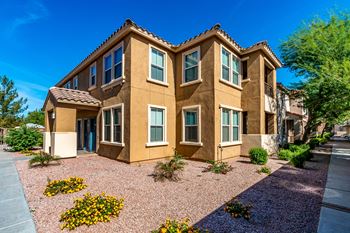 A tan stucco house with a blue door and windows.